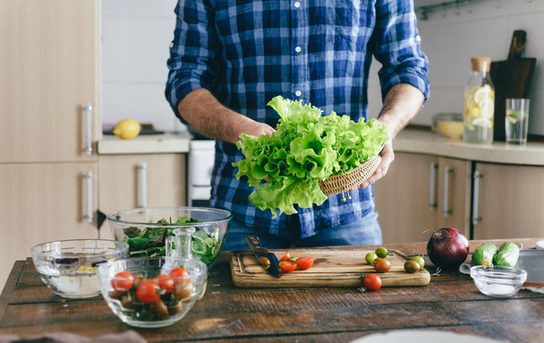 Man cooking summer salad at home in the kitchen. Healthy food concept - Fotoğraf, Görsel