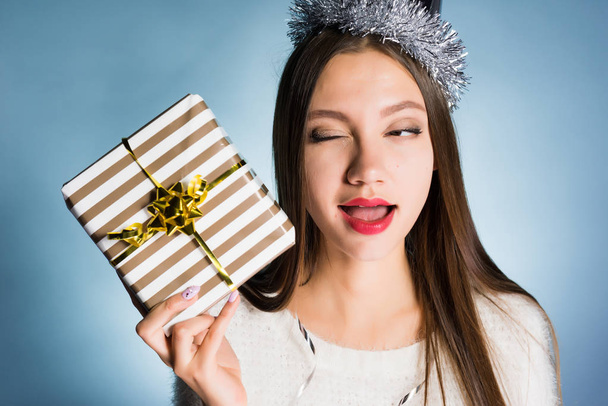 A woman on a blue background is preparing to open her New Year gift - Foto, Imagem