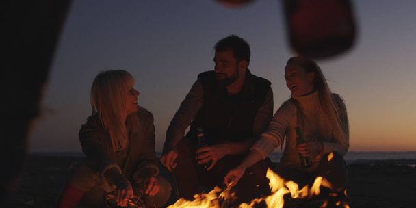 Group of young people having fun at beach around bonfire on sunset - Фото, зображення