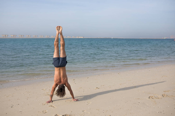 Young man doing handstand on the beach. - Foto, Imagem