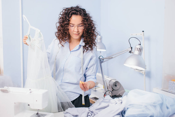 dressmaker sewing breeds to nightgown at work - Fotó, kép