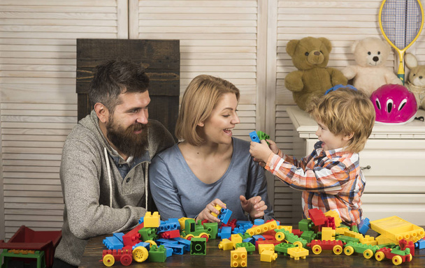 Parents and kid with happy faces hold colorful bricks. - Foto, Bild