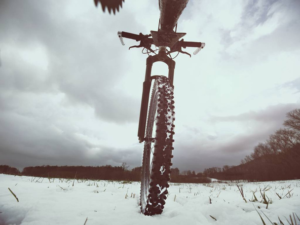 Tobillo bajo extremo vista cercana a la bicicleta de montaña bloqueada en el sendero helado nevado. Vista panorámica extrema
 - Foto, imagen