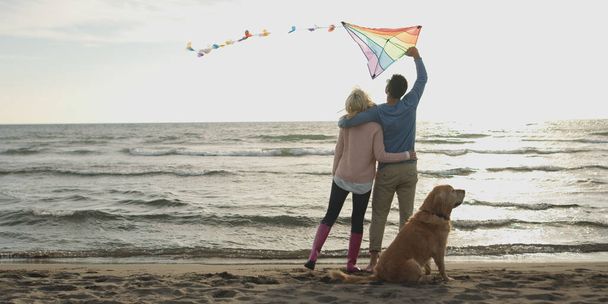 couple with dog having fun on beach on autmun day - Foto, Imagem
