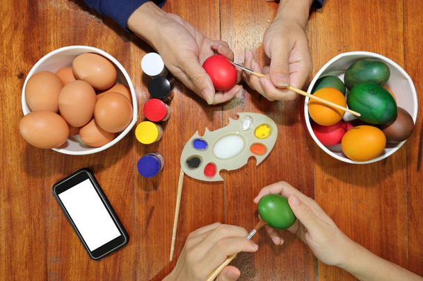 Ręce członków rodziny mają dobry czas z barwienia jaj przygotować na Wielkanoc. - Zdjęcie, obraz