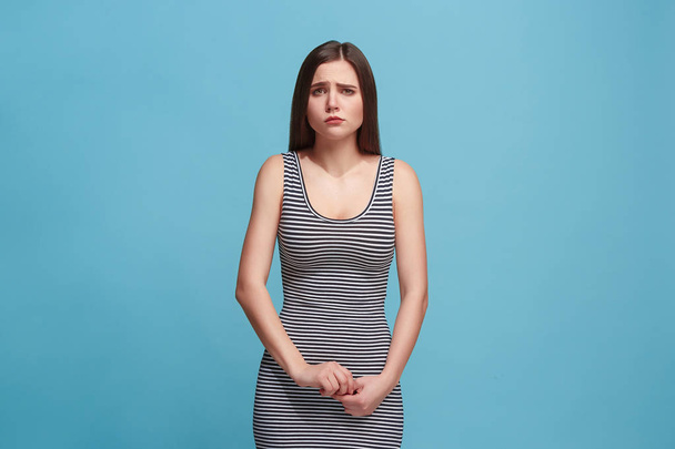 The awkward woman standing and looking at camera against blue background. - Photo, Image