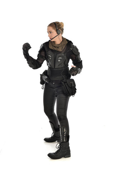 retrato de cuerpo entero de soldado femenino con armadura táctica negra, aislado sobre fondo blanco del estudio
. - Foto, imagen