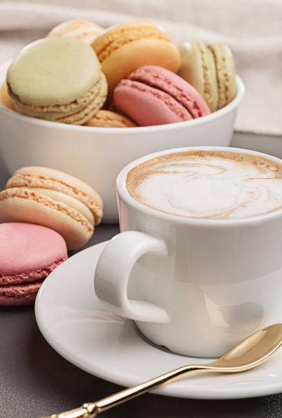White cup of fresh coffee, creamer, spoon and macaroons in  cup. - Фото, зображення