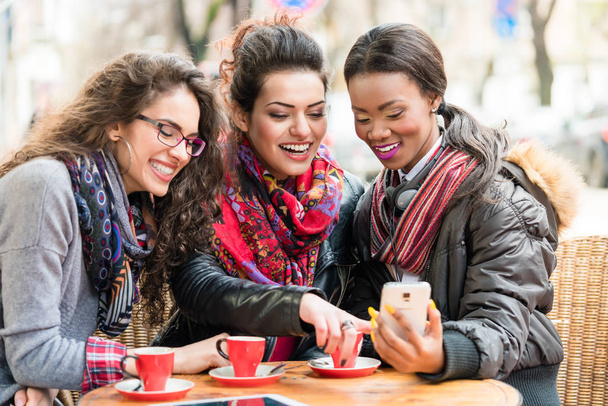 Vrouwen in café tonen van foto's op smartphone - Foto, afbeelding