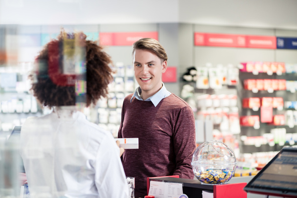 Nuori mies hymyilee ostaessaan hyödyllisen lääkkeen
  - Valokuva, kuva