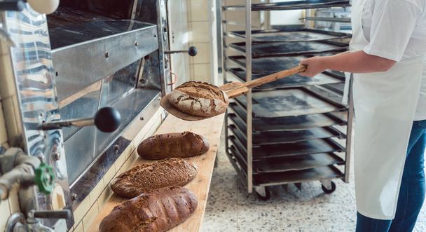 Frau in Bäckerei bringt Brot an Bord - Foto, Bild