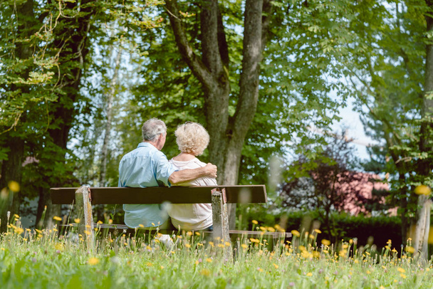 Ρομαντικό ζευγάρι ηλικιωμένων κάθεται μαζί σ ' ένα παγκάκι, σε μια ήσυχη καλοκαιρινή μέρα - Φωτογραφία, εικόνα