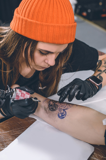 Mujer artista del tatuaje durante el proceso de tatuaje
 - Foto, Imagen