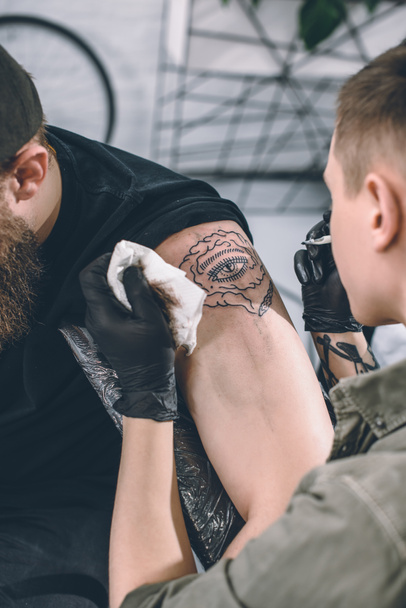 Татуировщик работает над наплечником в студии
 - Фото, изображение