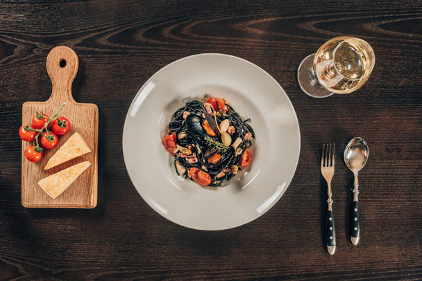 top view of spaghetti with cuttlefish ink, squid and mussels with octopus on table - Fotografie, Obrázek
