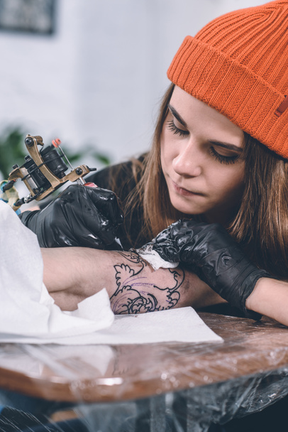 Maestro de tatuaje de niño y mujer durante el proceso de tatuaje en el estudio
 - Foto, Imagen