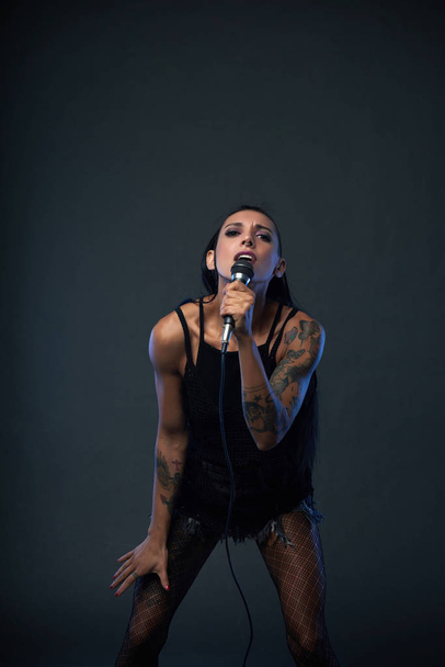 Portret van vrouwelijke zanger met tatoeages op haar armen - Foto, afbeelding