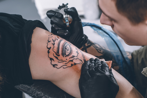 Tatuaje artista en guantes trabajando en estudio
 - Foto, Imagen