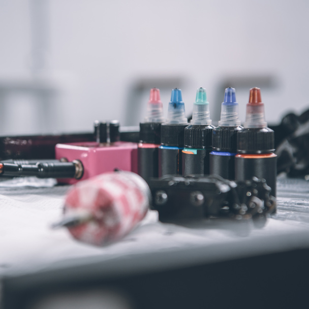 Tätowiermaschine und Flaschen mit bunter Tinte  - Foto, Bild