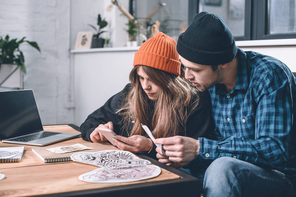Hombre y mujer eligiendo diseño de tatuaje en estudio
 - Foto, Imagen