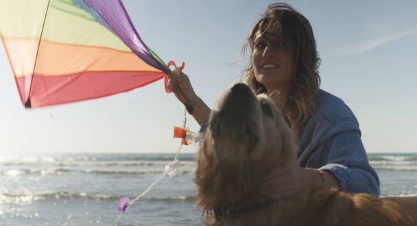 Beautiful Young Woman with dog Holding A Kite at Beach - Фото, изображение