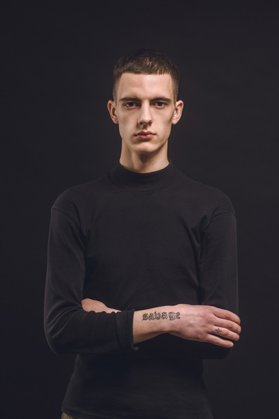 Впевнений чоловік з татуйованими руками ізольовані на чорному
 - Фото, зображення