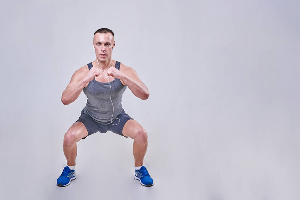 Handsome man performing squats in sportswear  - Photo, image
