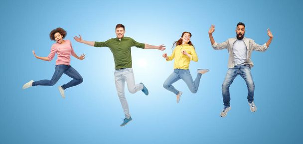 happy people or friends jumping in air over blue - Foto, Imagen