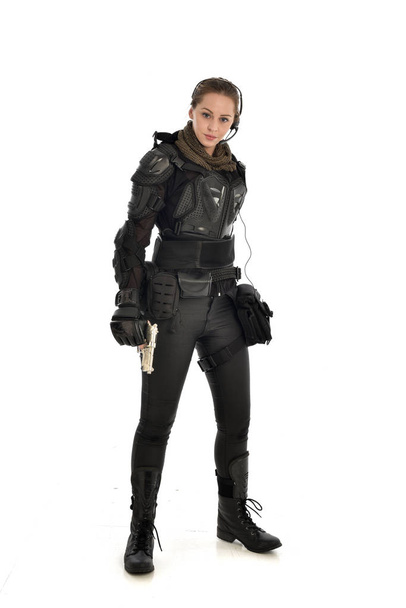 retrato de cuerpo entero de una soldado vestida con armadura táctica negra sosteniendo un arma, aislada sobre fondo blanco del estudio
. - Foto, Imagen