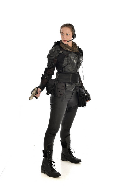 portrait complet d'une femme soldat portant une armure tactique noire tenant un pistolet, isolée sur fond de studio blanc
. - Photo, image
