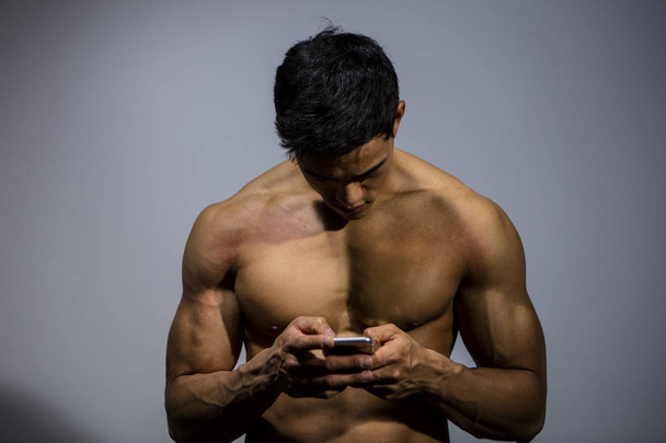 Fitness Model kijken naar mobiele telefoon scherm - Foto, afbeelding