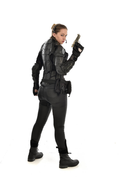 full length portrait of female  soldier wearing black  tactical armour holding a gun, isolated on white studio background. - Photo, image