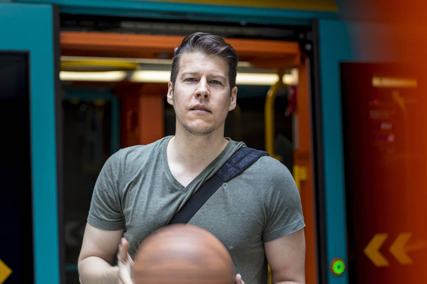 Hombre deportivo con un baloncesto saliendo de un tren subterráneo
 - Foto, imagen