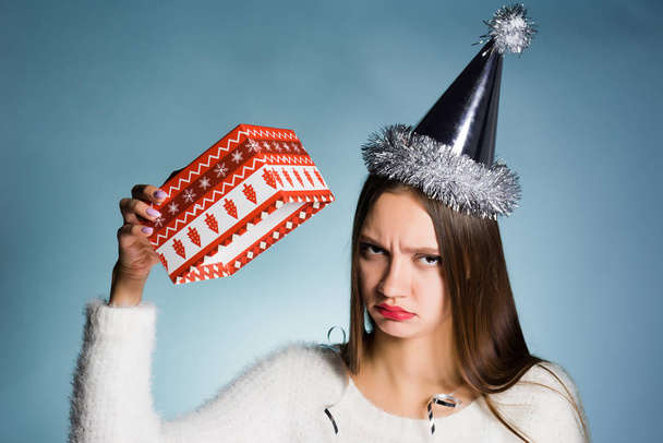 a frustrated woman in a festive hat holds an empty gift box - Photo, image
