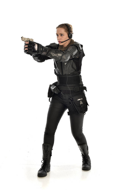 portrait complet d'une femme soldat portant une armure tactique noire tenant un pistolet, isolée sur fond de studio blanc
. - Photo, image