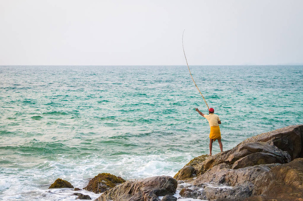 Fisherman catches fish on a tropical beach - Foto, afbeelding