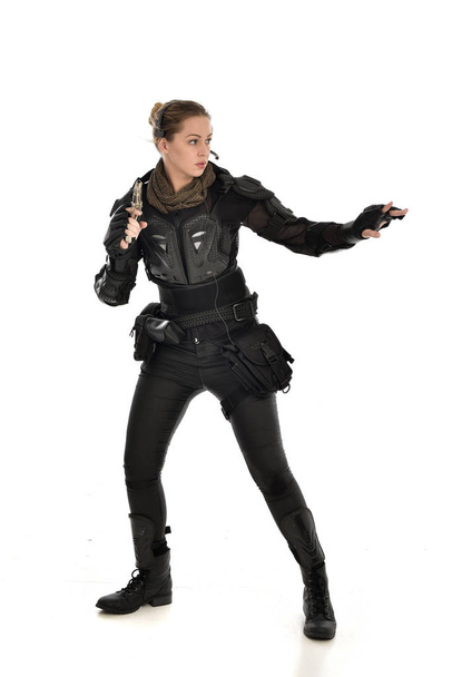 Ganzes Porträt einer Soldatin in schwarzer taktischer Rüstung mit Gewehr, isoliert auf weißem Studiohintergrund. - Foto, Bild