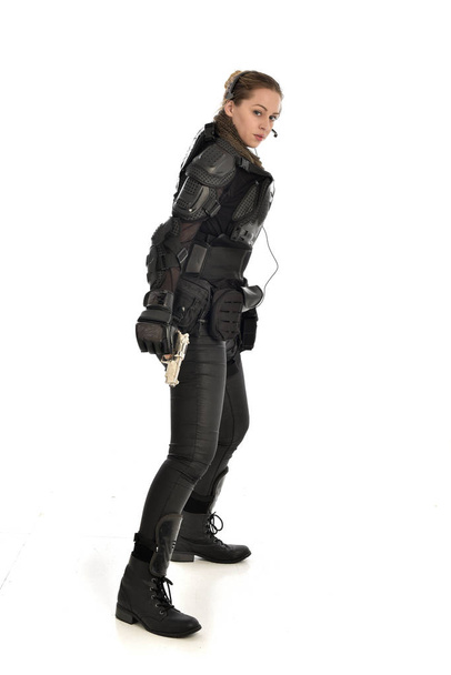 retrato de comprimento total de soldado vestindo armadura tática preta segurando uma arma, isolado no fundo do estúdio branco
. - Foto, Imagem