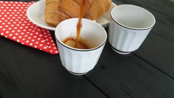 Kaffee wird in eine Tasse gegossen, ein Croissant - Filmmaterial, Video
