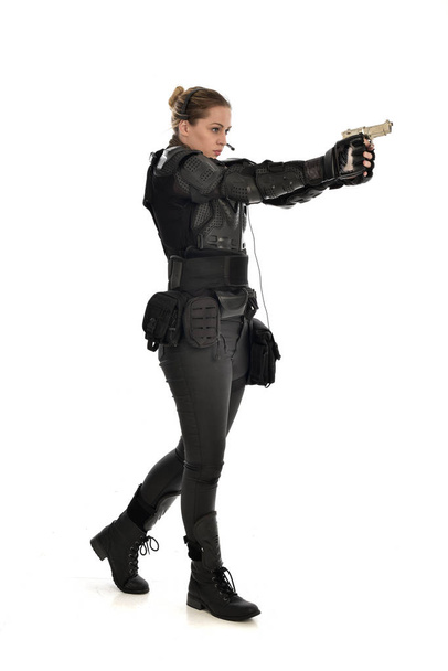 Ολόσωμο πορτρέτο του γυναίκα στρατιώτη που φορούσε μαύρο τακτικό πανοπλία κρατώντας ένα όπλο, απομονώνονται σε φόντο λευκό στούντιο. - Φωτογραφία, εικόνα