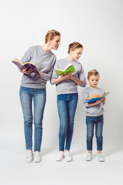 mother and daughters in similar clothing with books isolated on grey - Valokuva, kuva