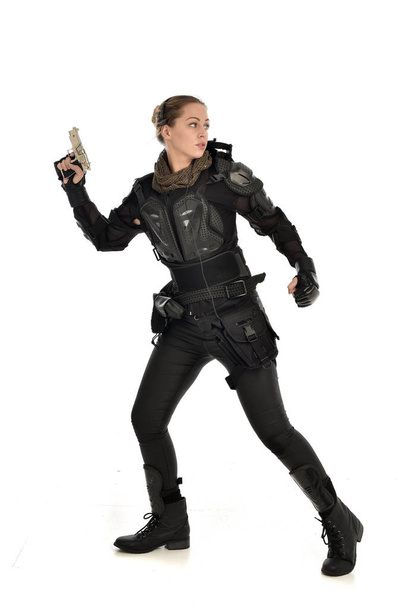 портрет жінки-солдата в чорній тактичній броні, що тримає пістолет, ізольований на білому фоні студії
. - Фото, зображення