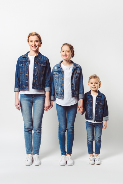 happy family in similar denim clothing standing in row and holding hands isolated on grey - Photo, Image