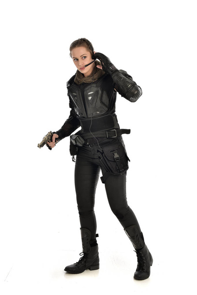 портрет женщины-солдата в чёрной тактической броне, держащей пистолет, изолированный на белом фоне студии
. - Фото, изображение