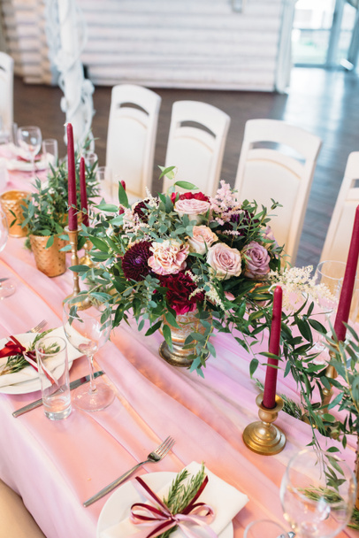 Mesas para invitados con sillas de colores claros decoradas en color rosa con flores, velas, jarrones de oro y eucalipto
 - Foto, Imagen
