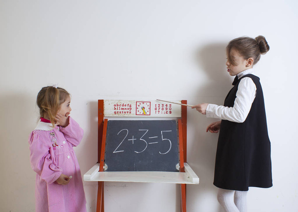 Niña enseñando matemáticas a un niño más pequeño
 - Foto, Imagen