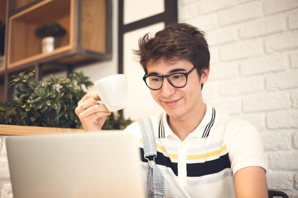joven hombre guapo en la cafetería con el ordenador portátil
  - Foto, Imagen
