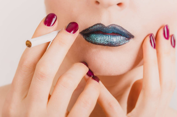 Close up of woman face with cigarette and tinsel makeup - Фото, изображение