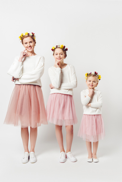 beautiful mother and daughters in similar clothing with floral wreathes on heads isolated on grey - Φωτογραφία, εικόνα