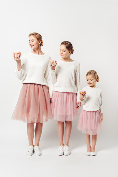 family in similar clothing with sweet doughnuts isolated on grey - 写真・画像